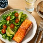 Colorful balanced meal with salmon, salad, and fresh fruit representing healthy eating habits after 40