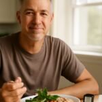 Middle-aged adult managing type 2 diabetes with a healthy meal and blood glucose monitor on a kitchen table